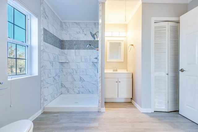 bathroom featuring vanity, tiled shower, ornamental molding, and toilet