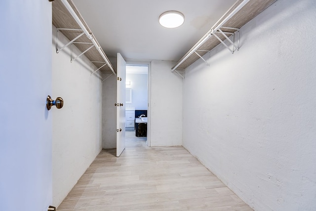 walk in closet with light hardwood / wood-style floors