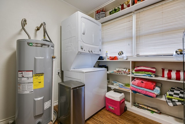 laundry room featuring laundry area, crown molding, wood finished floors, stacked washer / dryer, and water heater