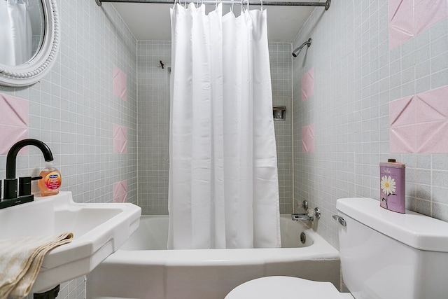 full bath featuring toilet, tile walls, a sink, and shower / tub combo