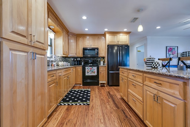 kitchen with decorative backsplash, wood finished floors, light stone counters, black appliances, and ornamental molding