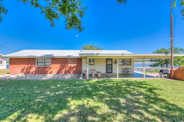 ranch-style home with brick siding, a front lawn, a patio area, and metal roof