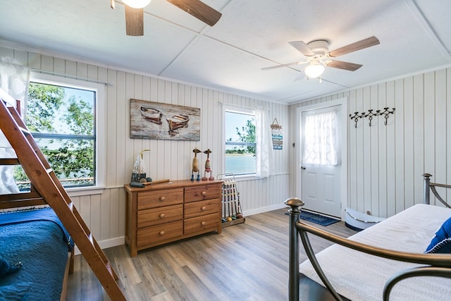 bedroom featuring light wood-style floors, baseboards, multiple windows, and a ceiling fan