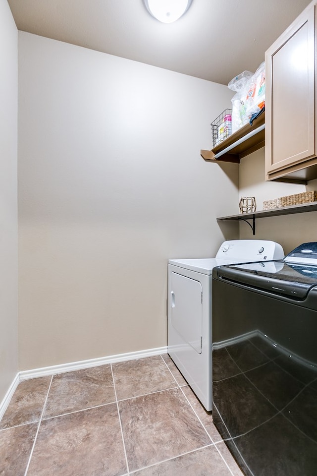 laundry area with light tile patterned floors, washer and clothes dryer, and cabinets