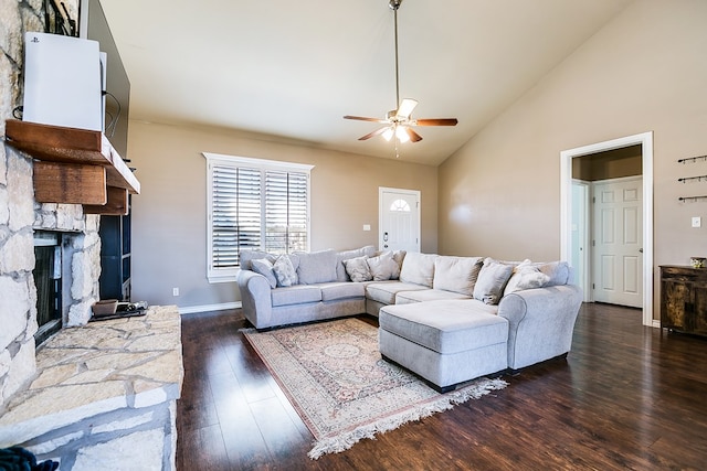 living room with ceiling fan, a stone fireplace, high vaulted ceiling, and dark hardwood / wood-style flooring