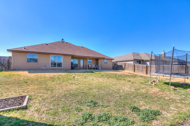 rear view of property with a patio, a yard, and a trampoline