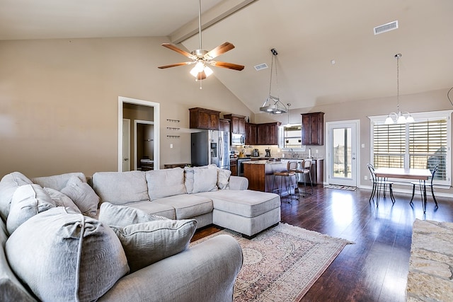 living room featuring dark hardwood / wood-style flooring, beam ceiling, ceiling fan with notable chandelier, and high vaulted ceiling