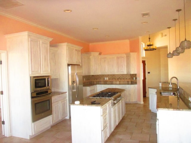 kitchen with sink, stainless steel appliances, decorative backsplash, a kitchen island, and decorative light fixtures