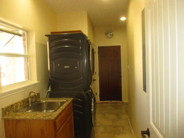 clothes washing area featuring stacked washer and clothes dryer and sink