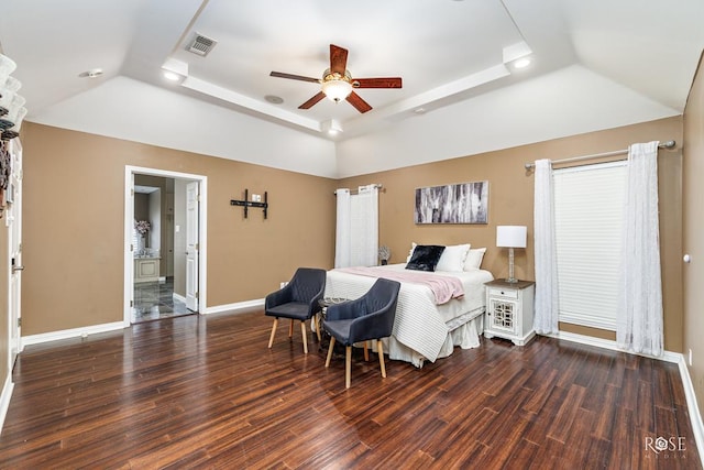 bedroom with dark hardwood / wood-style floors, vaulted ceiling, and a raised ceiling