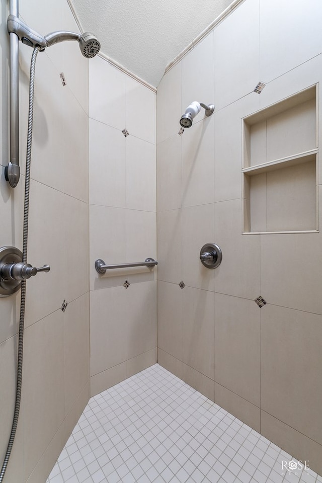 bathroom featuring a textured ceiling and tiled shower