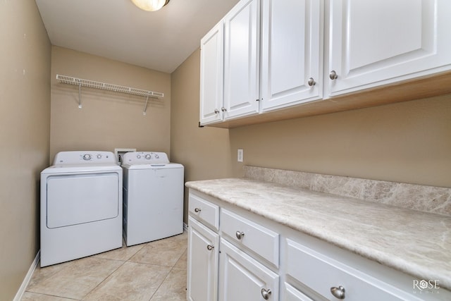 laundry area with washer and clothes dryer, cabinets, and light tile patterned flooring