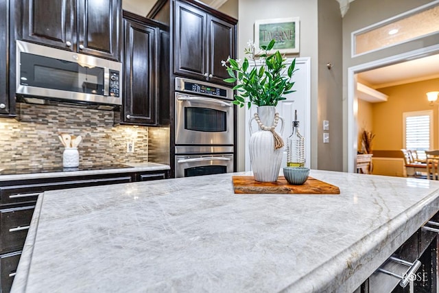 kitchen with stainless steel appliances, crown molding, backsplash, and light stone counters