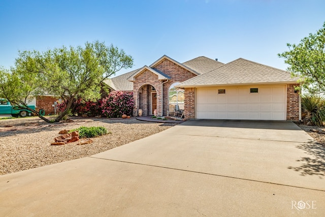 view of front of property featuring concrete driveway, a garage, a shingled roof, and brick siding