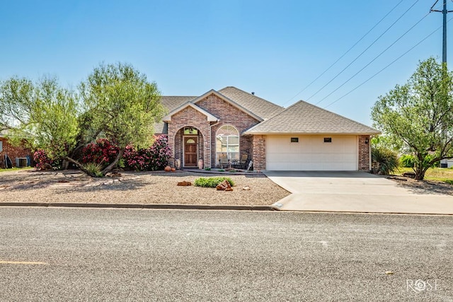 view of front of house featuring driveway, roof with shingles, a garage, and brick siding
