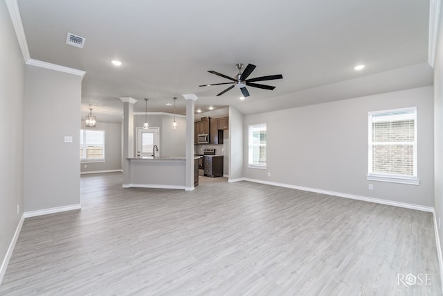 unfurnished living room with sink, ceiling fan with notable chandelier, light hardwood / wood-style floors, and a healthy amount of sunlight