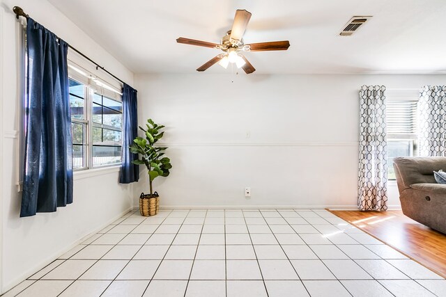 tiled spare room with ceiling fan and a wealth of natural light