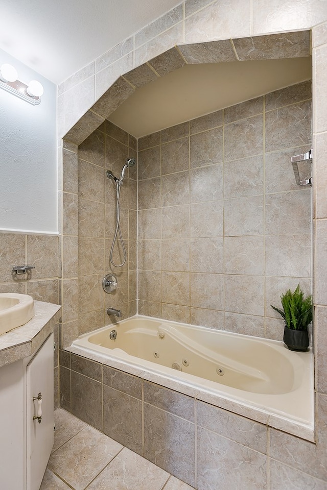 bathroom with tile patterned floors, tiled shower / bath, vanity, and tile walls