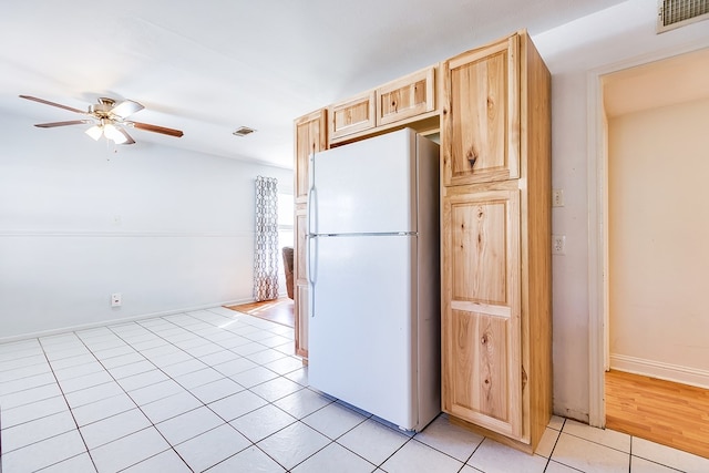 kitchen featuring light tile patterned flooring, ceiling fan, light brown cabinetry, and white fridge