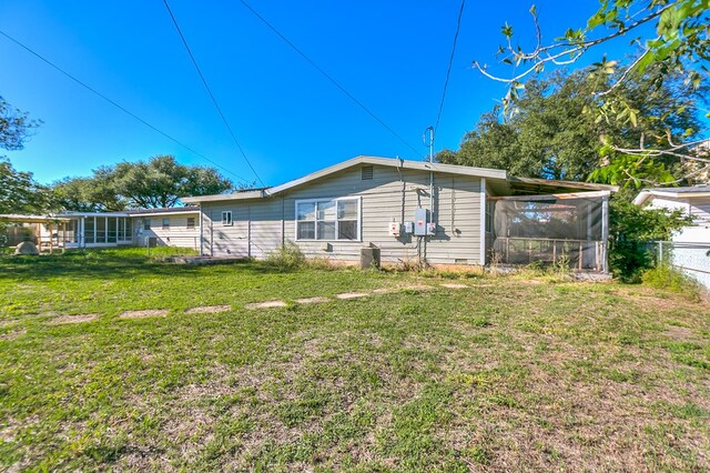 rear view of house featuring a sunroom and a lawn