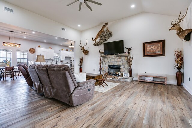 living room featuring vaulted ceiling, ceiling fan, a fireplace, and hardwood / wood-style floors