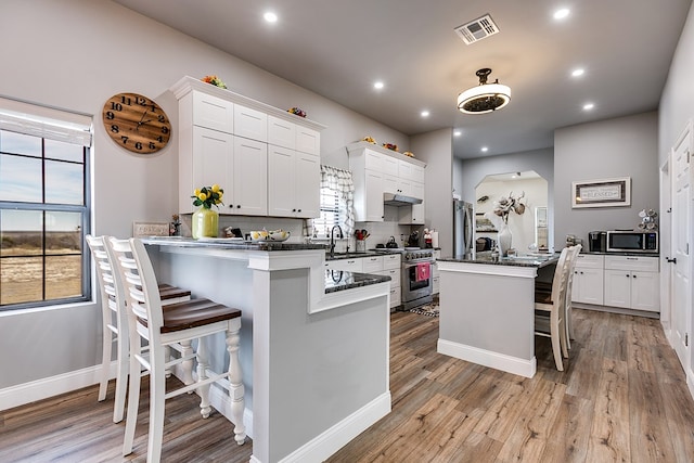 kitchen featuring stainless steel appliances, white cabinetry, tasteful backsplash, and a breakfast bar area