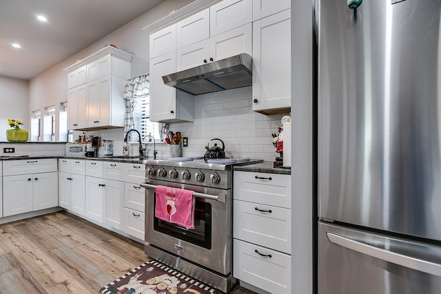 kitchen with sink, appliances with stainless steel finishes, white cabinets, decorative backsplash, and light wood-type flooring