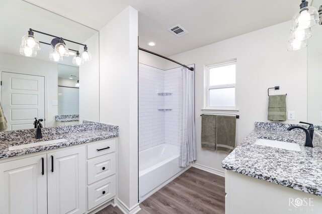 full bath featuring shower / tub combo, visible vents, a sink, and wood finished floors