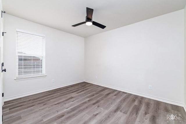 empty room featuring a ceiling fan, baseboards, and wood finished floors