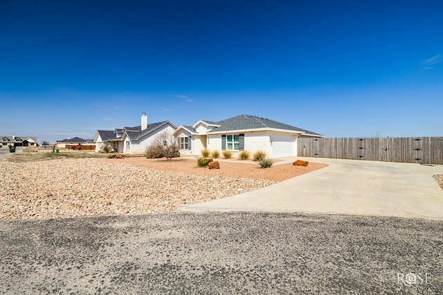 single story home featuring concrete driveway, an attached garage, and fence