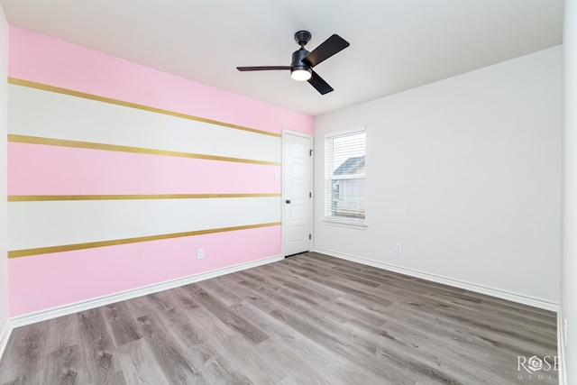 unfurnished room featuring wood finished floors, a ceiling fan, and baseboards