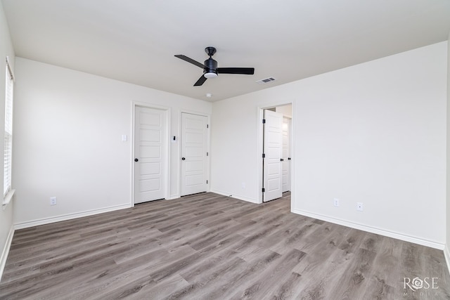 unfurnished bedroom featuring visible vents, ceiling fan, baseboards, and wood finished floors