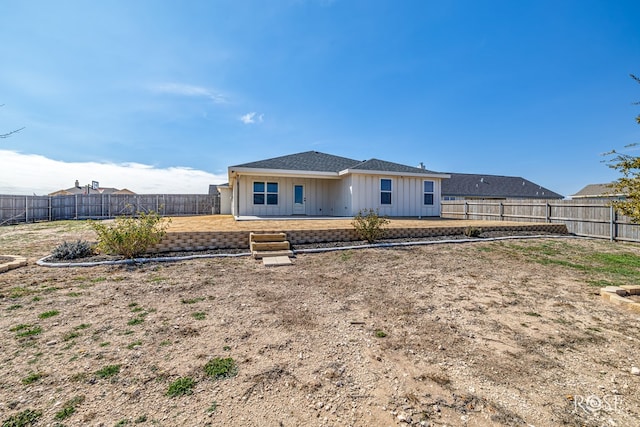 back of property with board and batten siding and a fenced backyard