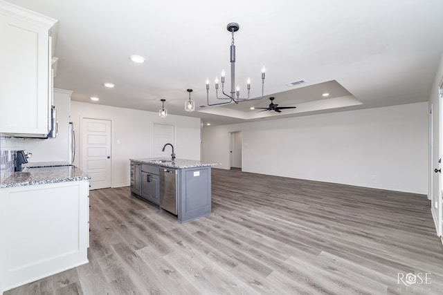 kitchen with dishwasher, a center island with sink, visible vents, and white cabinets