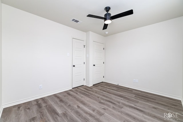 unfurnished room featuring ceiling fan, wood finished floors, visible vents, and baseboards