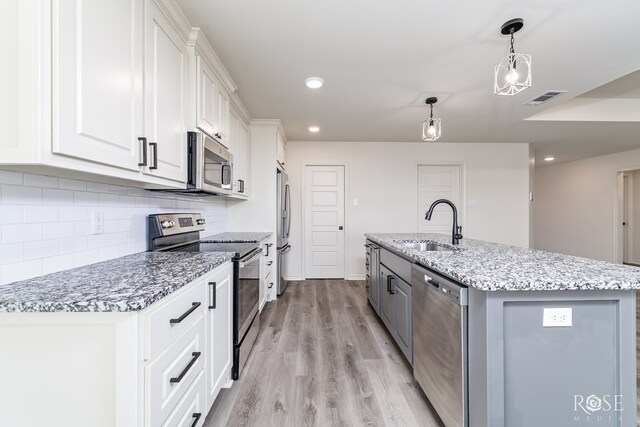 kitchen with visible vents, appliances with stainless steel finishes, white cabinetry, a sink, and light wood-type flooring