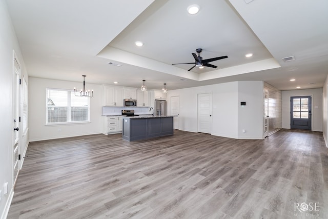 kitchen with wood finished floors, stainless steel appliances, a raised ceiling, and open floor plan