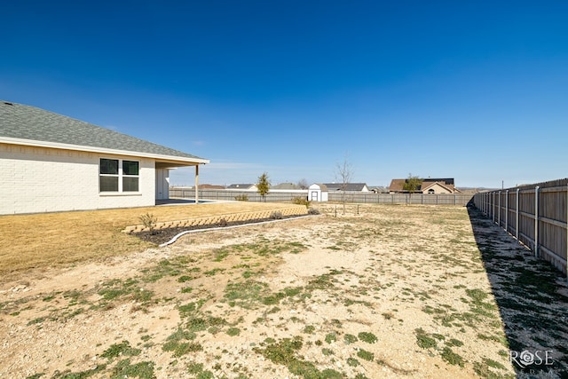 view of yard featuring a storage shed, a fenced backyard, and an outdoor structure