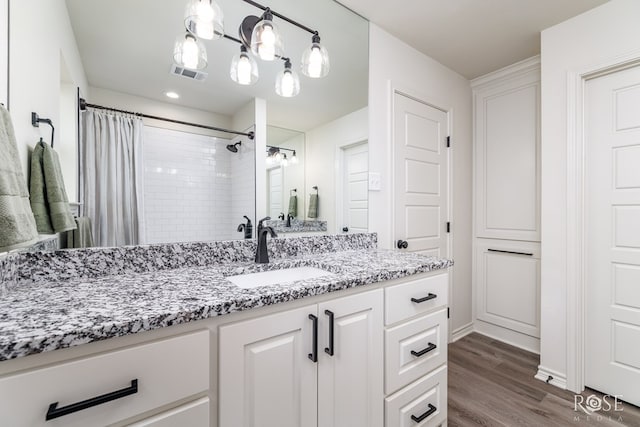 bathroom with vanity, curtained shower, wood finished floors, and visible vents