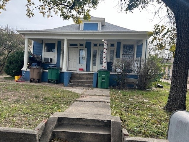 bungalow-style home featuring a front yard, covered porch, and cooling unit