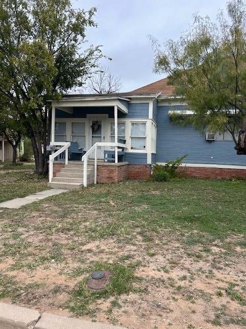 view of front of home with a wall mounted air conditioner and covered porch