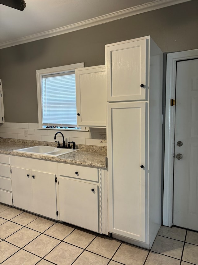 kitchen with sink, light tile patterned floors, white cabinetry, ornamental molding, and decorative backsplash