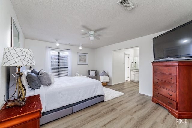 bedroom featuring ceiling fan, light hardwood / wood-style floors, a textured ceiling, and ensuite bathroom