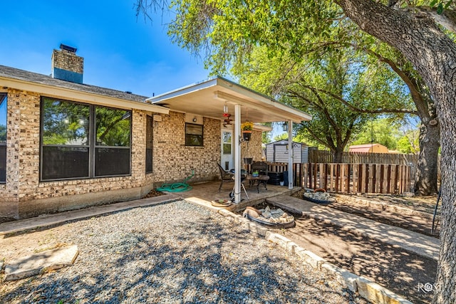 view of front of home with a storage unit and a patio