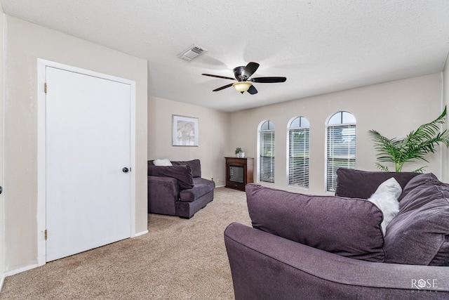 carpeted living room featuring ceiling fan and a textured ceiling