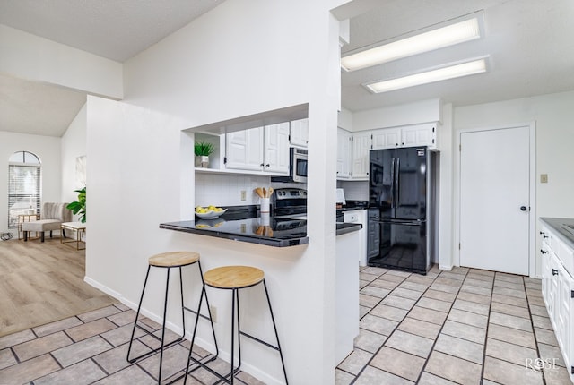 kitchen with white cabinetry, appliances with stainless steel finishes, a breakfast bar area, and kitchen peninsula