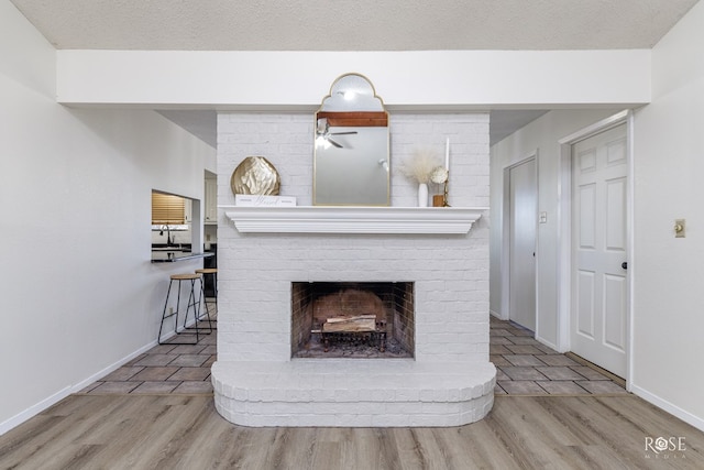 details featuring hardwood / wood-style flooring, a brick fireplace, and a textured ceiling