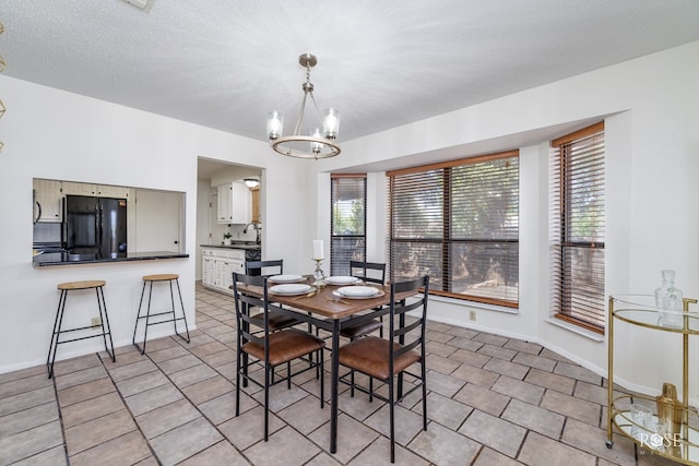 dining area featuring a notable chandelier, a wealth of natural light, sink, and a textured ceiling