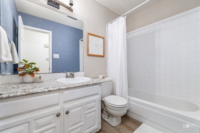 full bathroom with shower / tub combo, hardwood / wood-style floors, vanity, a textured ceiling, and toilet