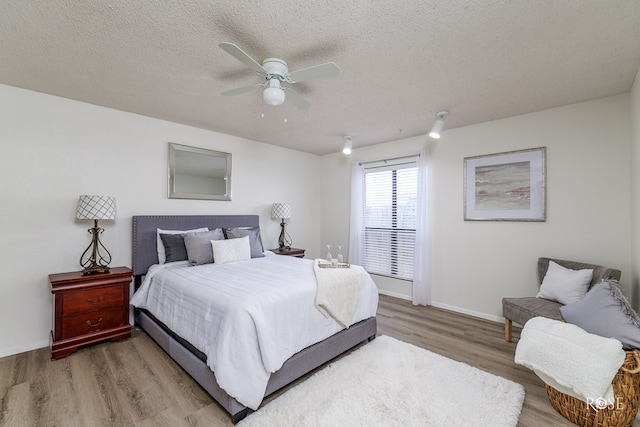 bedroom featuring ceiling fan, light hardwood / wood-style flooring, and a textured ceiling